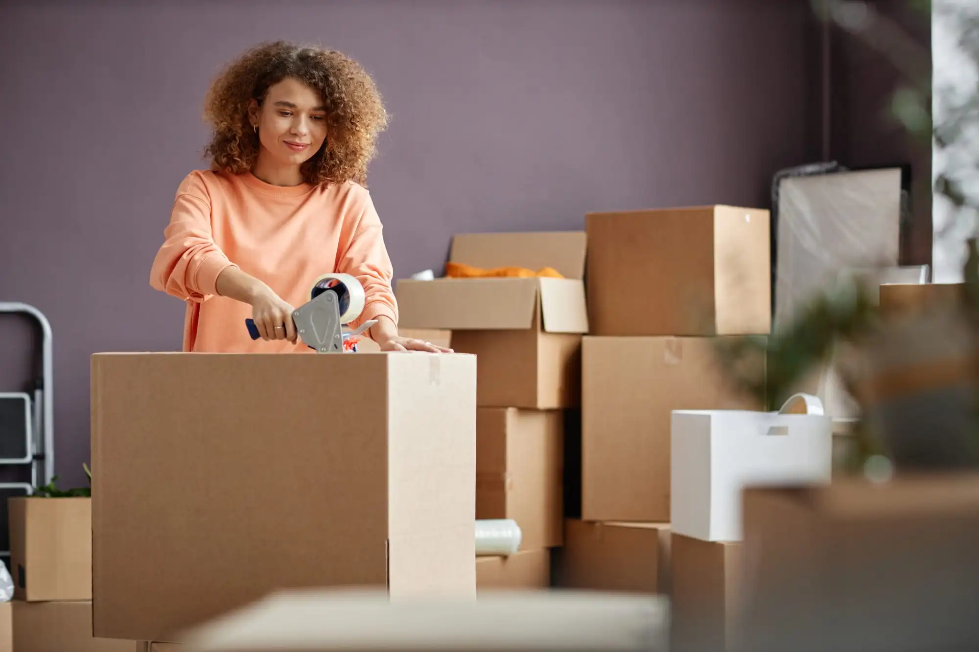 A woman taping boxes on moving day