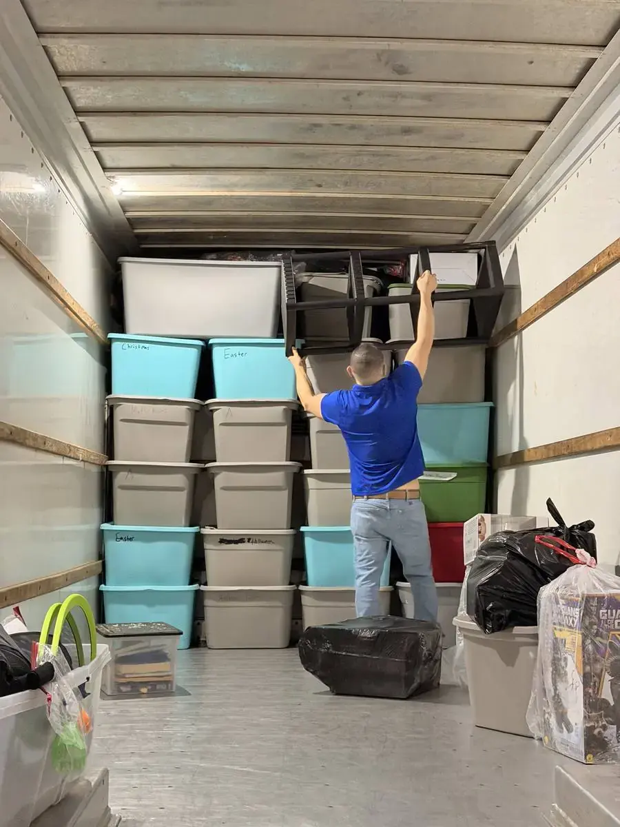 Box truck in a residential driveway with padded furniture at the open rear door in front of a single-story Central Florida house